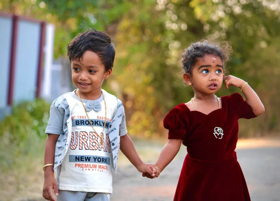 A brother and sister holding hands outside